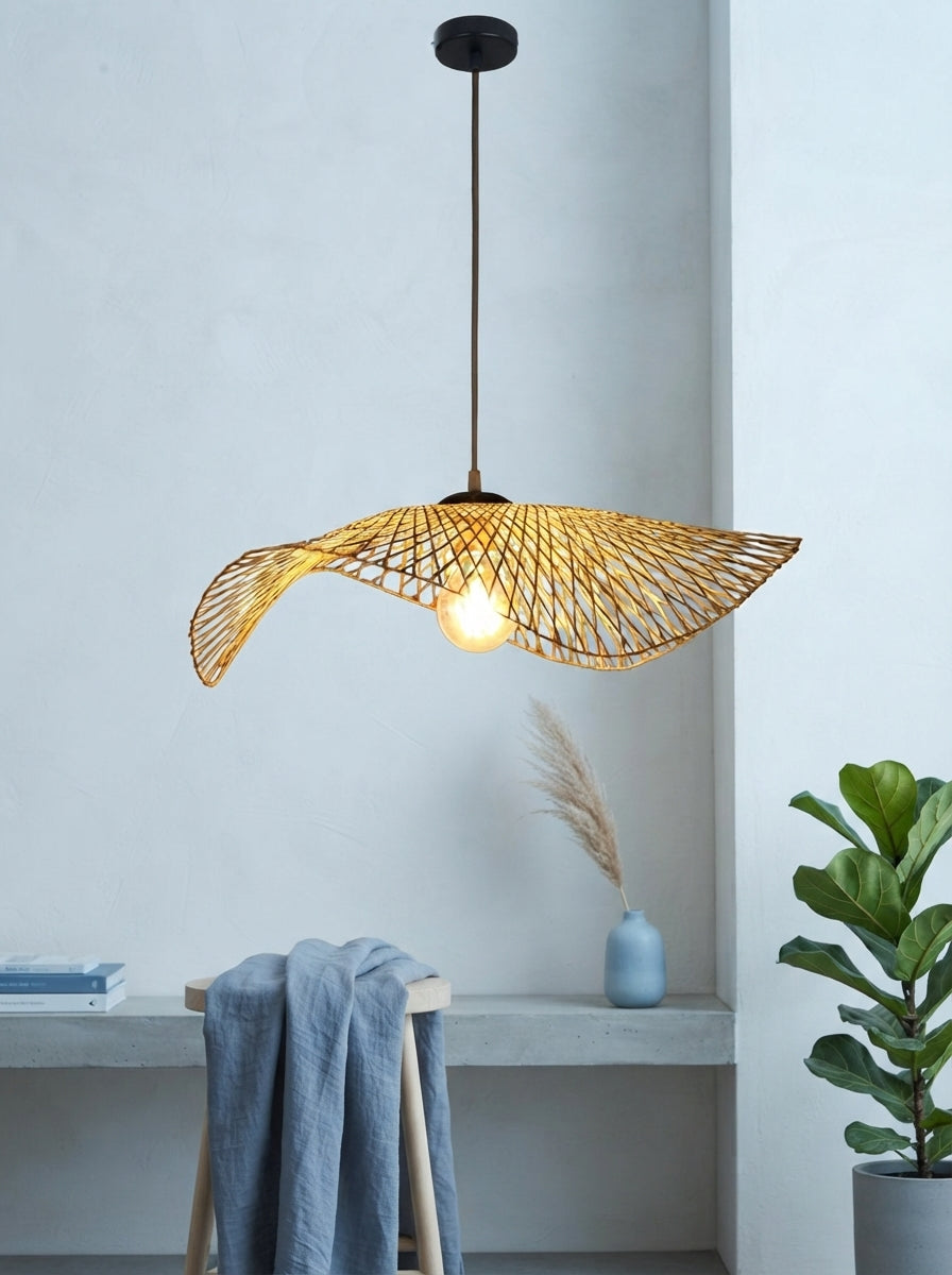 A handcrafted bamboo pendant light with intricate weaving and a warm golden finish suspended in a bright, modern studio space